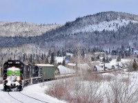 Three ex-CP RS-18's (two recently repainted into an SP Black Widow-inspired paint scheme) lead a train consisting of 72 flat cars holding 48 windmill blades (as well as 1 loaded woodchip car up front), as it rounds a curve along the Restigouche River, headed for nearby Matapedia and interchange with the CN. These windmill blades are destined for Texas and represent a new business for the Société du chemin de fer de la Gaspésie, which runs this scenic ex-CN line.