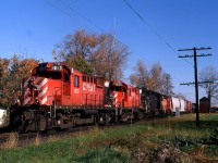 
On a cool clear October morning, I was spending time trackside until my C&O assignment went to work at 1600. I had been over at the C&O station to check on how many cars our job, Local 3 the Courtright Turn would have, when the yard foreman told me there was a CP westbound getting close and he had a southside set-off. So I walked around the block and waited for this guy to show up. RS18u's 1813-1826 with leased Conrail GP38 7823 and idling CP 8153 ( for Windsor use) were pulling ahead to allow the trainman to make the 'cut' on the set off. The old CPR interlocking tower was still standing, with it's wood and insul-brick rotting away. The CP train order signal can be seen above the 3rd car, set for "Y" in both directions. At one time this interlocking was named East End. When the old tower was removed from use, with it's rods and levers, the diamond was then controlled in the concrete block structure which is on the north side of the Windsor Sub. To the left of the nose of 1813 is the C&O's Dover spur which serviced a few customers along Colborne and William Streets (Cash & Carry lumber and Dover Flour Mill).