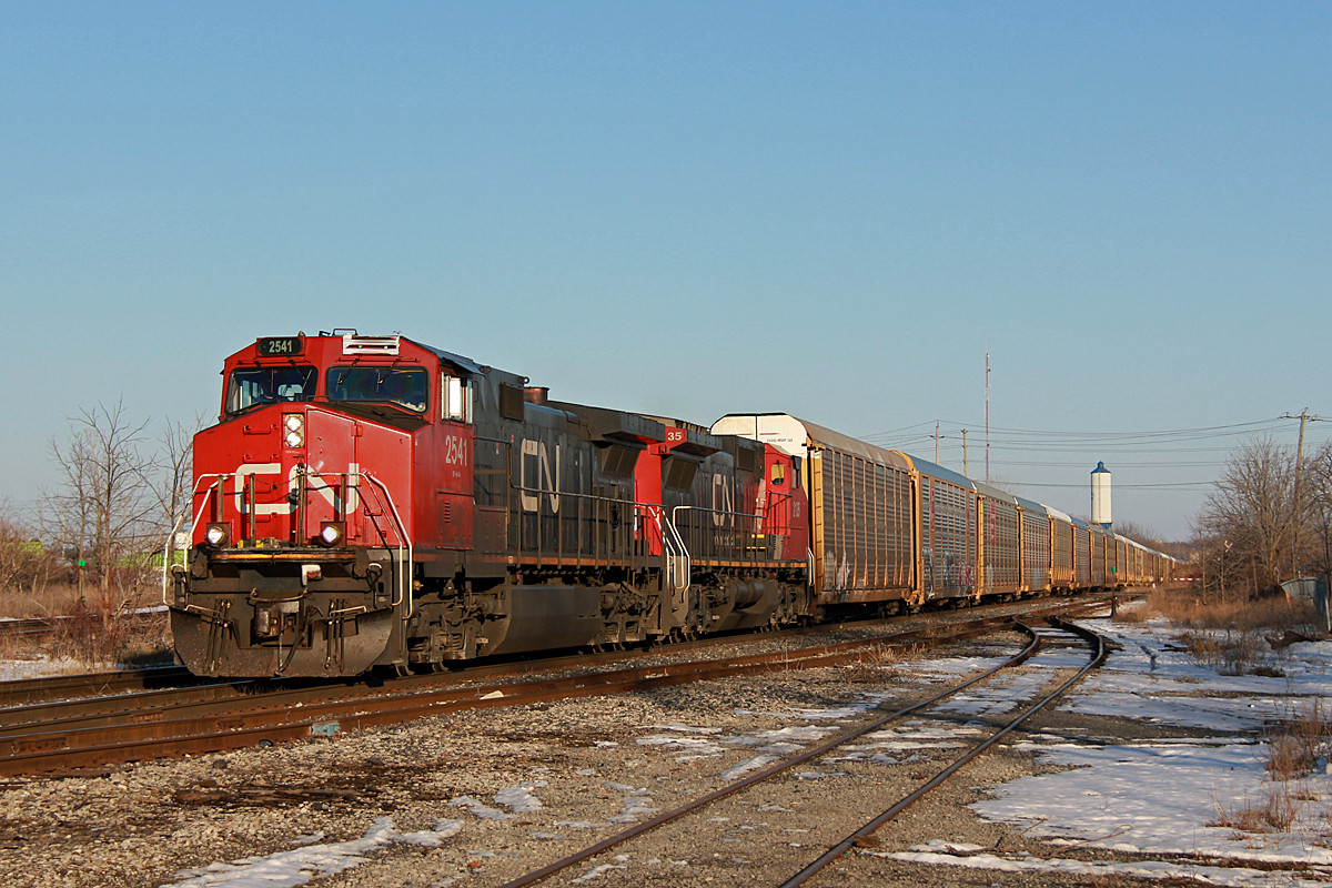 Catching westbound freights sunlit on CN in Niagara is a very difficult task, as it is rare the opportunity is ever presented. If there is a train to do it though, it is normally 232, which runs very occasionally. Upon waiting for Via 98/Amtrak 63 "Maple Leaf," my friend's radio indicated a train was going over the Mile 27 detector on the Stamford Sub while the Amtrak approached. A signal indication at Glenridge and further radio chatter showed there was indeed a westbound freight coming.

About 15 minutes after the Amtrak was CN 232 with CN 2541 and 2135. The throw off here was all the autoracks were loaded, which is something I have not noticed on previous 232's I've seen. Under 50 autoracks were in tow however, which is quite normal for this train. I'm not sure of the story behind 2541's conductor side numberboard, but the saying here goes, "it doesn't matter if it's duct tape, fixed is fixed."

The presence of westbound evening freights on the Grimsby Sub has been a consistently rare thing since the 2008 recession effectively reduced the number of trains in half. At the time, 331 and 338 were occasionally later than normal and would appear in the evening, and 332 was often an evening freight. 232 is practically 332's replacement, but barely runs in comparison to 332 during the pre-recession days. Nonetheless, it was quite the treat to get a decently sunlit shot of a westbound for once on the Grimsby Sub. If my memory is correct, this would be the first time I was able to get a photo of such a thing, despite having seen it probably a dozen times before after the recession came about. Previous opportunities like the washout at Jordan in 2014 never came to fruition, as 331 and 422 never appeared until night fall. This time was entirely by chance, since my main purpose of coming here was for the Amtrak believe it or not. CN had recently trimmed up the ROW here so I had to take advantage of it, and luckily the right day was chosen. Considering I would've just gone home after the Amtrak without my friend's scanner around, I think it's time to finally invest in replacing my broken scanner.