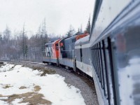 UPGRADE AT CRUISERS. Terra Transport Mixed Extra 935 West has just crossed under the TCH overpass in Bishops Falls on April 16, 1988 and is climbing upgrade at Cruisers Brook, said to be the steepest grade on the entire 547 Mile Newfoundland Railway. Departing Bishops Falls at 11:00 AM, the two NF210's (935 and 927) leave with passenger only equipment (Baggage 1308 and Coach 764) until four container units were picked up in Grand Falls. The only travellers to make the entire 138 mile journey to Corner Brook were the photographer and his friend Paul who was delighted to experience his first ride on a Newfoundland train. One other, a cabin owner, got on at Millertown Junction and soon departed in several feet of snow at Gaff Topsail. The hospitality and friendliness of the Newfoundland crews were beyond compare, with conductor Carl Dillon inviting us both back to the caboose and allowing us to ride in the cupola for several dozen miles. 