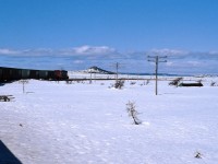 REACHING THE SUMMIT - Terra Transport Mixed Extra 945 West reaches Summit on April 20, 1987. At 1550 feet above sea level, it is the highest point of the 547 mile narrow gauge Newfoundland Railway on the entire  mainline. With the roof of a cabin barely visible, the heavy snowfall from the winter is still piled several feet high, belying the fact that spring is well underway elsewhere on the Island. The only passengers to travel there that day were the photographer and his then girlfriend (now wife) on their very first trip on a Newfoundland train.This image and it's modern day counterpart can be seen in my first book, RAILS ACROSS THE ROCK - A Then & Now Celebration of The Newfoundland Railway (2013) published by Creative Book Publishing.
