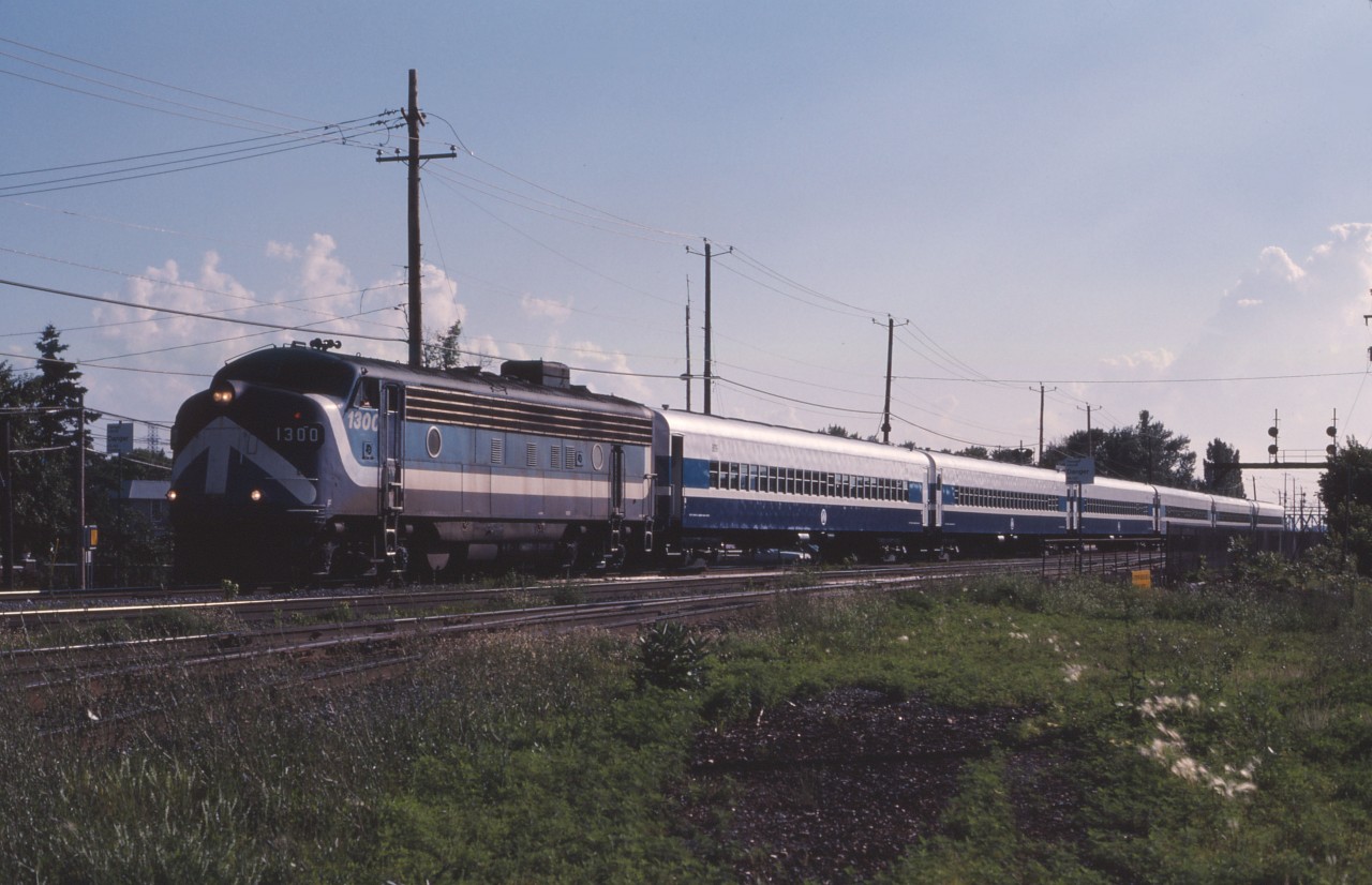 During the "Oka Crisis" in 1990, the Mercier bridge in the Montreal area was closed, causing traffic chaos. As a "relief valve", a commuter train was temporarily operated between Montreal and St-Isidore over CN lines using former CP commuter equipment borrowed from West Island commuter service.

Here we see one of two weekday trains with Montreal Urban Community FP7 1300 passing the CN station in St. Lambert.