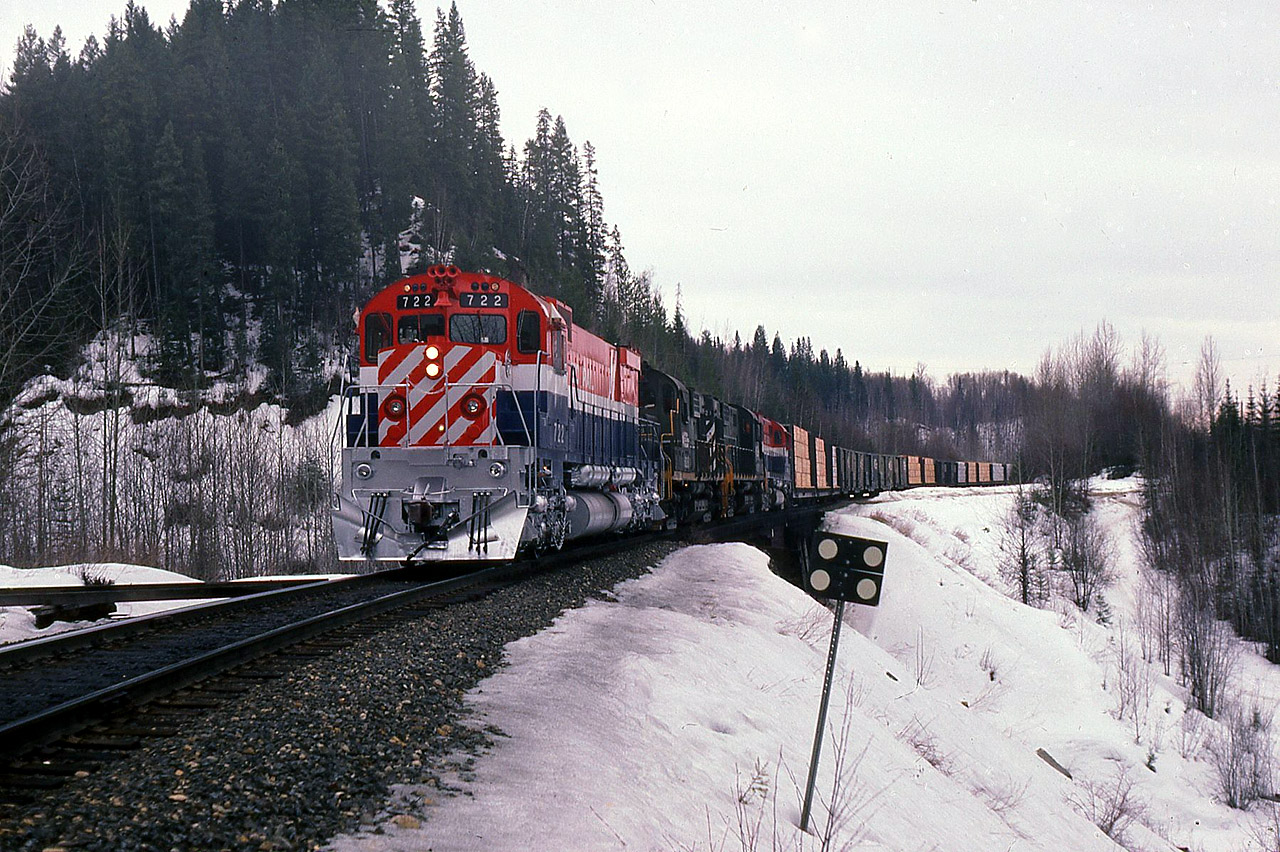 March 16 1985, BCR 722 freshly painted and overhauled,with trailing units 618-621-632, poised on Stone Creek bridge at mile 444.3 on the BC Rail Prince George subdivision. Without much delay I stopped the train for a quick photo opportunity. It was a rather dull morning and I opted to extinguish the ditch / corner lights, less confusion for the camera light meter. The bridge over Stone Creek was a "glue-lam" structure with concrete waterway underneath. Station name sign "Stoner", mileage 443.9 is further back in the train.

  As can be seen the 722 is flying white flags and white class lights, train order authority to "run extra", Williams Lake to Prince George BC. On this day we were the symbol freight "VO" (Vancouver-Omnieca). BC Rail as well ran two other symbol freights northbound daily, "VP" (Vancouver-Peace) and the "VC" (Vancouver-Cariboo) these symbolized trains served the three regions of BC Rail. During the days of train orders and time table scheduled trains the symbol VP ran as train No23 from North Vancouver to Chetwynd. The two other north freight trains ran as "extra" although for operation purposes they had a scheduled time of operation. On this particular trip pictured, we would take rest at Prince George and then return to Williams Lake on the "OV" symbol usually running as a No.38 or a late No 36 on a "fourth class" time table schedule. No 23 the VP ran as a "third class" scheduled train.
