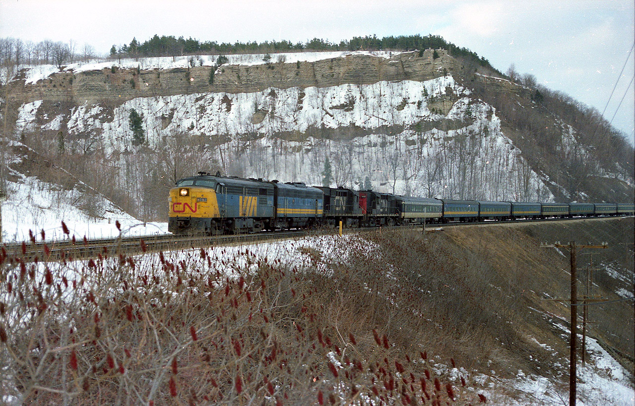 Typical 'back in the day' was this weekend passenger westbound #75. Sunday it could feature an unheard of today 20 coaches behind 4 units. In this view, VIA 6763, 6620 and CN 3107, 3125 pass Dundas Peak; not stopping at the Dundas Station, which is just out of sight to my left. In the foreground the sumach is beginning to get just a bit taller, after falling victim to the CN brushcutting every year until recent. Another couple of years and this angle would be lost to runaway foliage, as CN gave up on keeping the hillside clear. It must have been part of an austerity program or something.  It is a real shame. This was a great spot for photos.