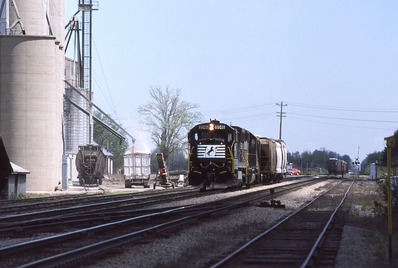Norfolk Southern and Norfolk & Western before that, and Wabash before that, all enjoyed the perks of serving certain customers along the CN Cayuga, Paynes and Chatham Subdivisions. While we were living in Chatham, I tried to find out when NS would be switching the elevator at Thamesville ( in 2017 known as AGRIS Co-op). The work was always done by westbound train 27 who would cut off the rest of his train east of Highway 2 and then perform a series of run arounds in order to accomplish the switch. After having pulled and respotted the customer, the power is about to tie back onto the outbound cars and then shove further east to put his train back together. The classic CN Thamesville station, although obscured by the movement, is still standing in this image. I never saw NS switch the other facility ( seen here to the left of the engines ) so obviously CN did that chore.