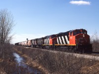 
Windsor-Toronto manifest 422 with it's usual heavy consist is about to cross the CP Windsor Sub. diamond west of Chatham in March 1987. Two GP40-2W's and two M420W's have salt loads and other mixed freight behind them as they hustle their way eastward. At the rear of the train are loaded auto racks from Chrysler that will be re-arranged at Toronto to go both east and west to their Canadian destinations.