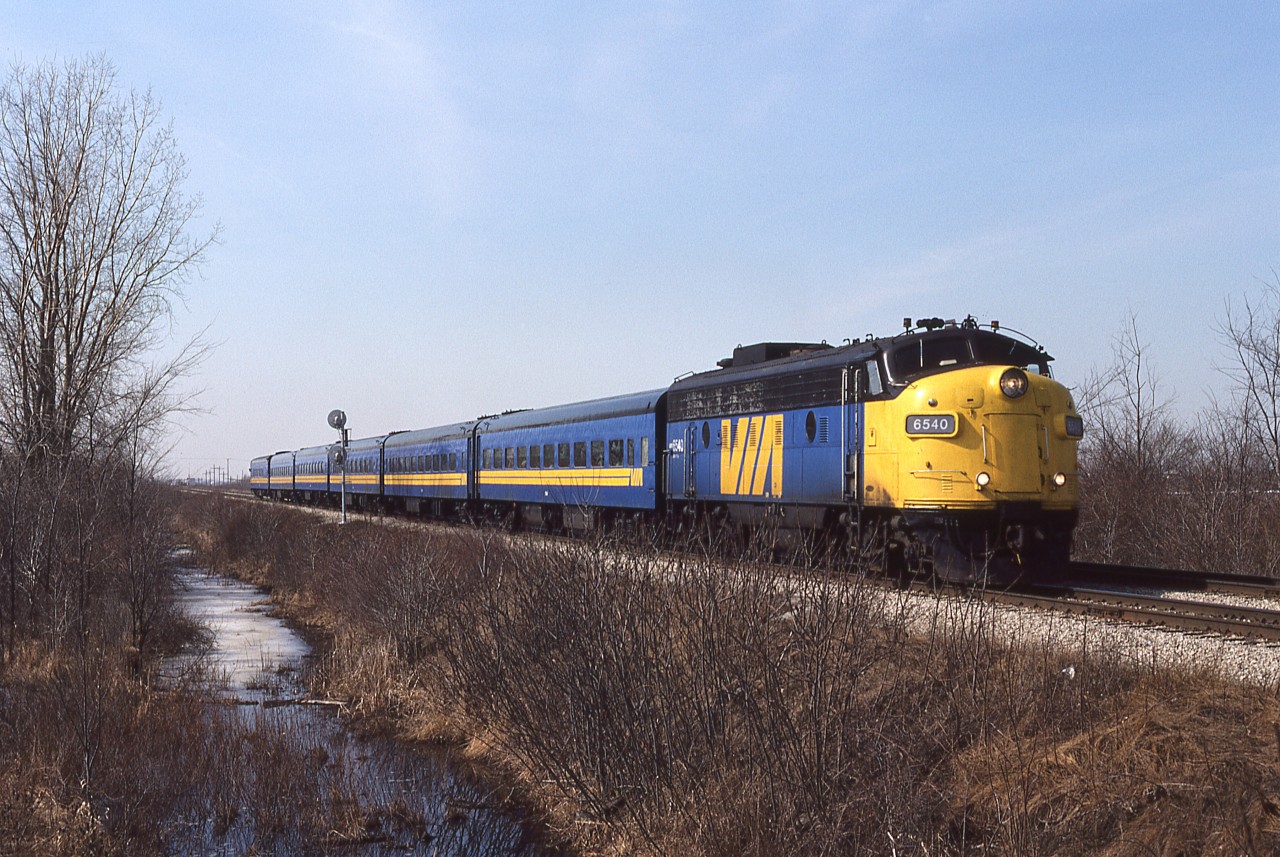 1987 would be the final year we lived in Chatham ( in November we moved to Bright's Grove, as CSX began to alter their Canadian operations). The first group of F40PH were in service, so I had stepped up my recon activities to catch the fading fleet of cab's and boosters. Once again, on a calm sunny day, I'm at the diamond crossing of the CN Chatham Sub and the CPR Windsor Sub. Train 74 is due and when I hear him at Prairie Siding, I get into position on the Windsor Sub, so as to obtain some elevation and keep the image 'clean'. Another single unit/6 car consist in the Corridor, as the aging FP9 drifts by the Absolute signal and clatters through the automatic interlocking. Happily, this engine exists today, on the Boone and Scenic Valley tourist operation, at Boone IA painted in C&NW colours.