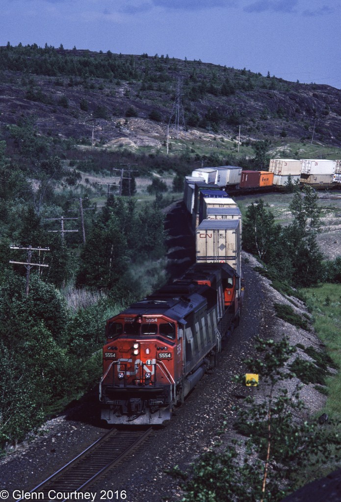CN train #101 led by SD60F 5554 approaches the diamond at Coniston on its way to western Canada. The rocks around Coniston offer lots of potential photo angles if you are willing to walk and climb a bit.