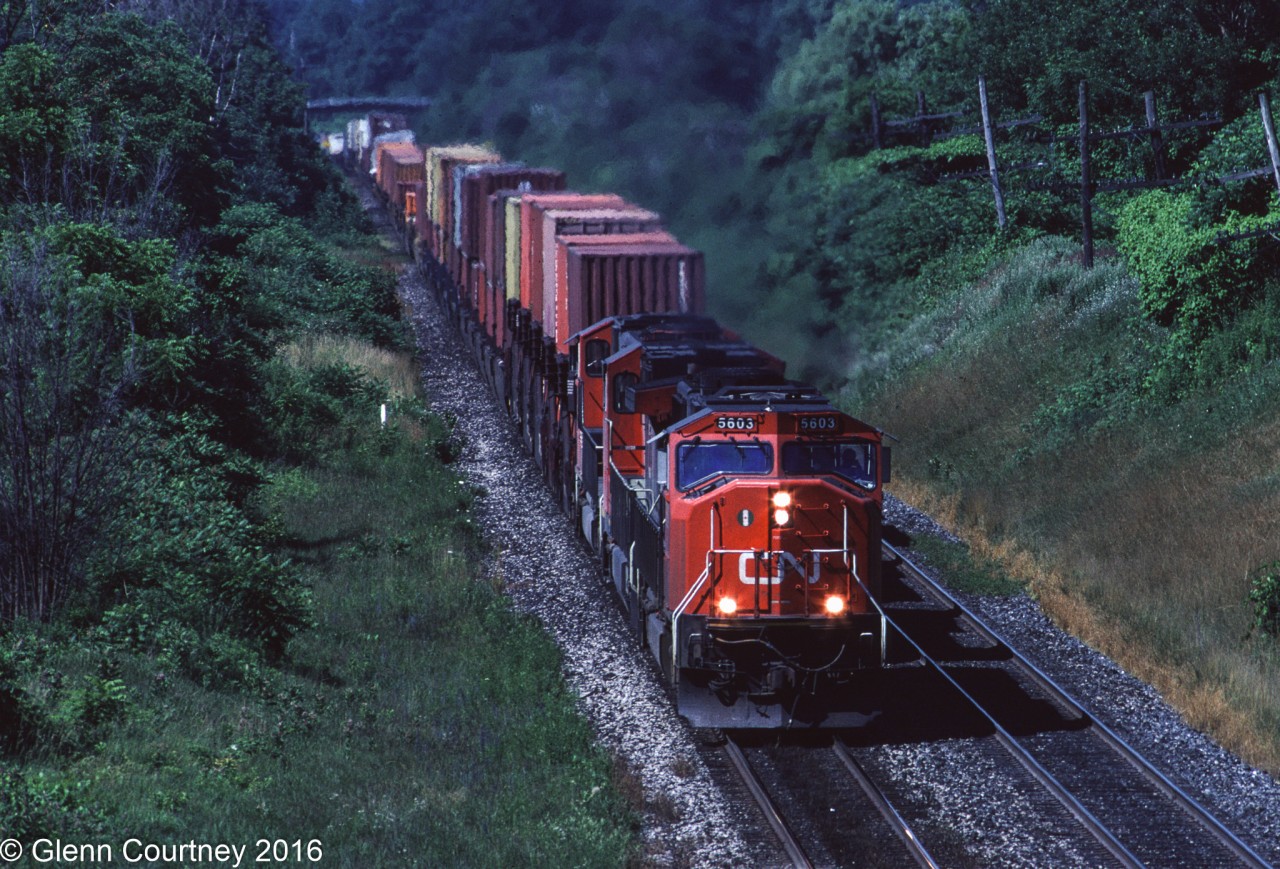 CN SD70I 5603 was only two years old when I caught it leading #148 approaching Aldershot. Today this scene is much changed with another main track and a longer lead to Aldershot Yard through here. You also will no longer see those trailers in the distance riding the rails in Canada.