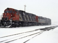 A Ron Hagemeister photo.
During a heavy spring squall, 3 freight engines wait for the call to duty. A pair of C630's are bracketing F7B 9191 near the east end of Sarnia Yard.