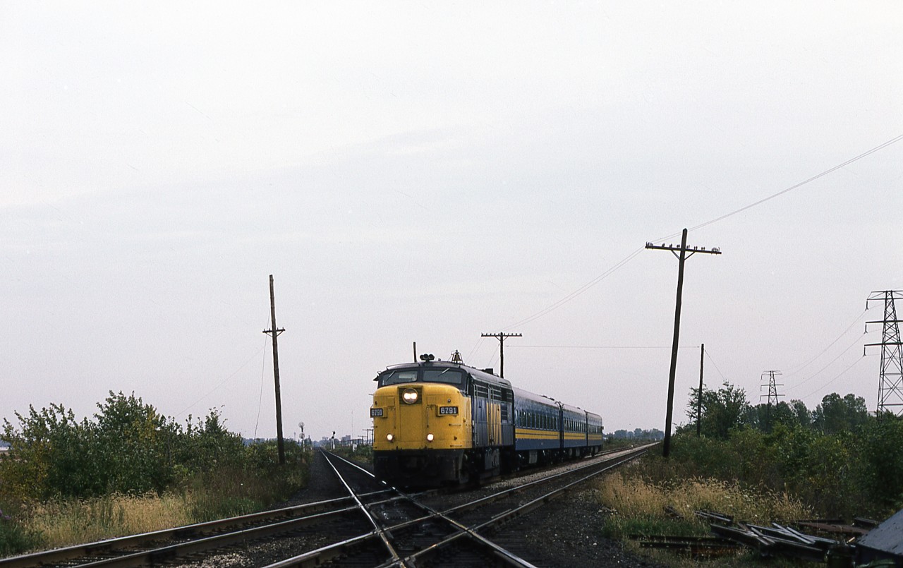FPA-4 6791 with a typical mid-week consist of 3 coaches as it glides across the CPR Windsor Subdivision a few miles west of downtown Chatham. The old round city water tower and the Wheels Inn resort are in the far left background, beyond 'Ringold' siding on CP. The MLW's days are numbered, as the first order of F40's is about 45 days away from being delivered.