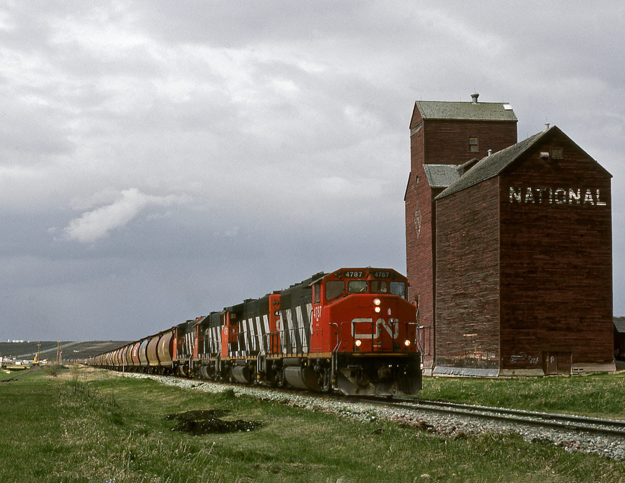 CN's Rycroft turn returning to Grande Prairie passes a derelict elevator as a storm brews in the north