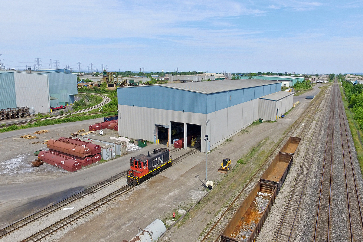 Seeing as the SW1200 rage is on, I thought I'd add another one of my 'now illegal' drone shots from last year. Unfortunately I've already uploaded most of my SW1200 shots, so this is about all I have left. On this day I was returning from a rather dull Bayview meet, and decided it was time to get a photo of 7304 at CN's Parkdale Yard. Here it sits, presumably shut down on this slow Saturday afternoon. This would be the last photo I would take not using a relatively high quality camera for the next two months, as my DSLR had disappeared the night before, and my drone would be out of service as well three days later due to a crash. Both my DSLR and drone are back today, though this photo definitely doesn't bring back the best of memories. It would be a long summer without any way to get decent photos.

In the right hand corner is the Niagara Escarpment, and Lake Ontario is also partially visible looking towards the transformer lines. The wye between the buildings stretches back behind them and skirts along the many steel industrial sectors that still somehow exist today. The track then merges back onto the Grimsby Sub at Stuart Street Yard. There was a time when manifests would actually work Parkdale Yard occasionally, though that changed and eventually the yard got its own dedicated switcher to switch around the Dofasco steel mill.

It's hard to believe it's been nearly three years since 7304 showed up here. It's been saved twice, in which it was rebuilt after a wreck with ONR 1517 in 1991, and then had its prime mover replaced a few years ago after the original one was damaged due to improper storage. It should be noted that although it is a rebuilt SW1200RM, the sides of the cab are painted red which is exclusive to 7304 among the rebuilt SW1200's. This occurred because of the wreck it had, and for some reason the cab sides were not repainted black. Though the red sides were standard among the unrebuilt SW1200RS units. None of those remain in service on CN so I guess 7304 can serve as a memory. It and 7311 are the only two SW1200 breed units in active service on CN today.