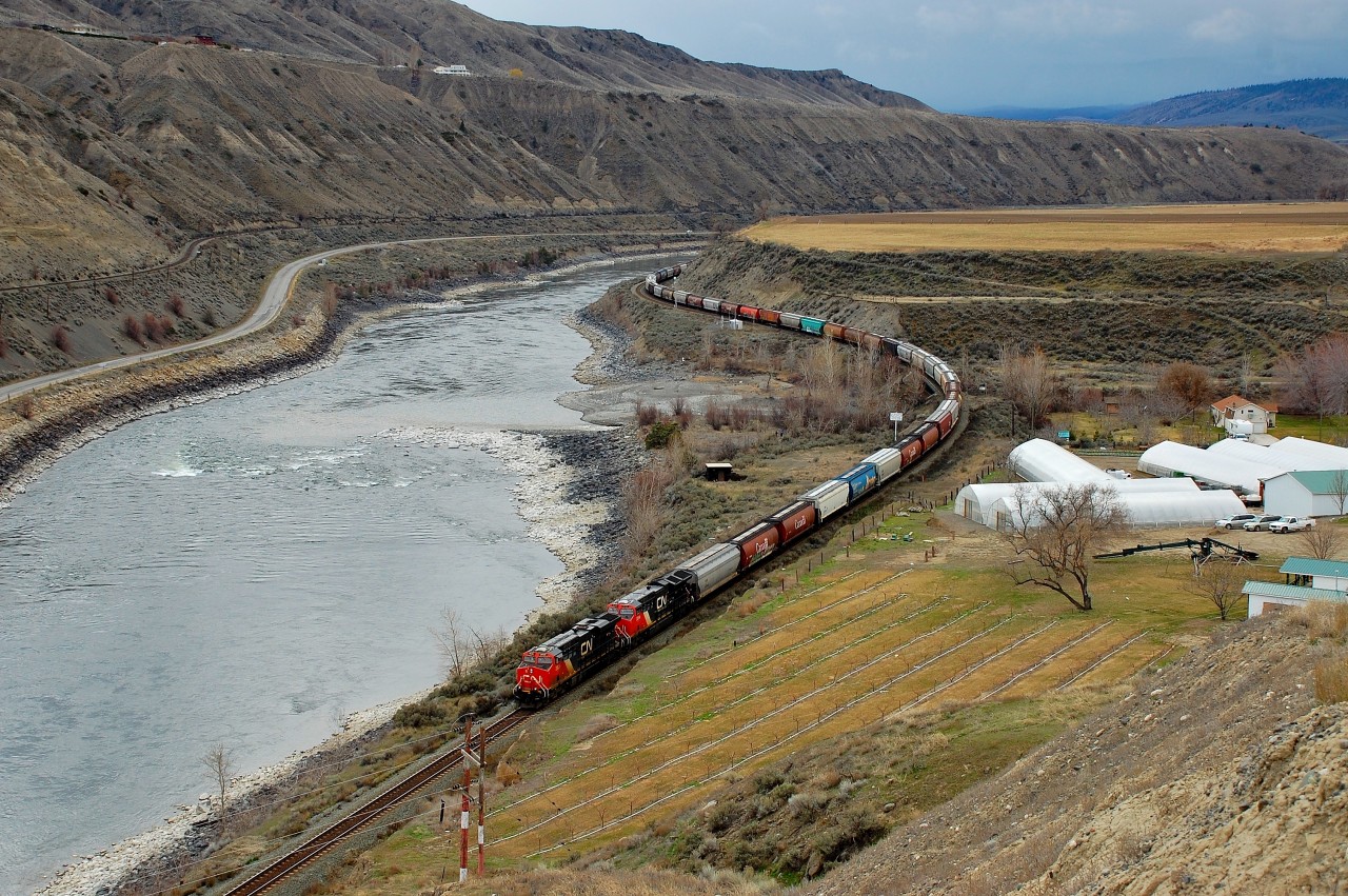 An eastbound load of grain empties is winding through Ashcroft alongside the Thompson River.