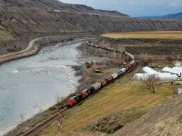 An eastbound load of grain empties is winding through Ashcroft alongside the Thompson River.