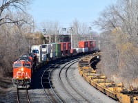 CN 3064 leads three other AC units (CN 3021, CN 2820 & CN 8100) as CN 120 rounds a curve in Ville St-Pierre. At right is a long string of empty well cars on the freight track of the Montreal Sub.
