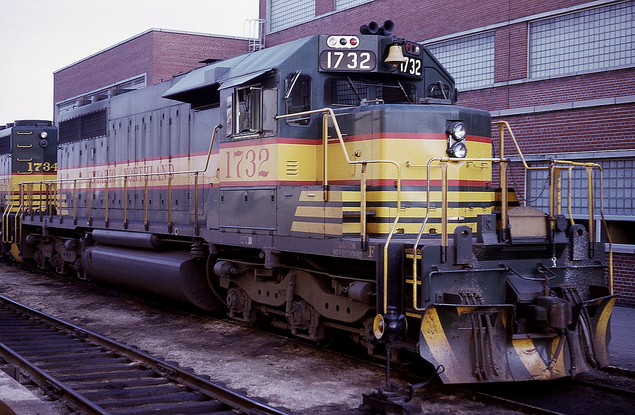 The second major paint scheme in the series on the Ontario Northland decorates ONR SD40-2 #1732 as it basks in a rather hot sun alongside the shop on May 23rd, 1975. The railroad had already begun changing over its identity to the famous Northland Chevron scheme the year before. This loco is gone now, having been in a wreck and subsequently scrapped in 2005.