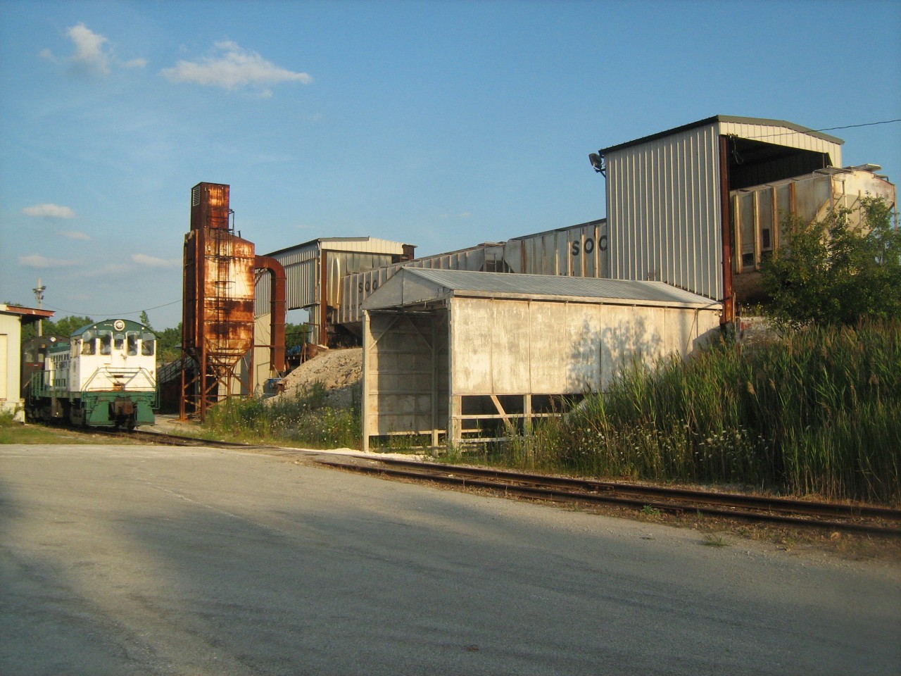 Herns alcos 300 (Ex. ETR 103) and 317 (Ex. AKMD 317) sit waiting for their next turn to climb the extremely steep, short hill to retrieve the empty Soo Line hoppers at right. This was an interesting operation, I'm not sure what substance was unloaded from the hoppers but it was a corrosive powder that could of had something to do with the former Allied/ General Chemical site which closed down in 2005. The cars always came from CP, maybe once a week, however this operation ended not long after this photo was taken. This was shot during an excursion by the Windsor Model Railroad Club on private property with permission.