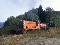 A Charles Begg photo. 
Baldwin model VO-1000 of Crown Zellerbach Canada Ltd brings an empty log train out of the shelter of the woods enroute to the camp for another load. The exact location, and hence direction, is unknown. But we do know that CZ bought this engine from the US Army Transportation Corp at Ogden UT in an auction late 1960. It was in service on Vancouver Island until being donated, locally, to the historical society. Unfortunately it was recently scrapped owing to deterioration. The 1943 product of Eddystone PA is carrying all the necessary equipment to quickly extinguish any spot fires along the right of way, starting with a goodly length of hose wrapped around the front handrail; and ending with the water car. 