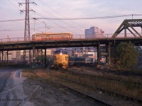  On its last Mile and a half into Toronto Union Station, Ontario Northland overnight sleeper from North Bay lead by FP7A 1517 ducks under Queen St as a TTC "PCC" streetcar passes overhead in the early morning of Oct 16th 1987.