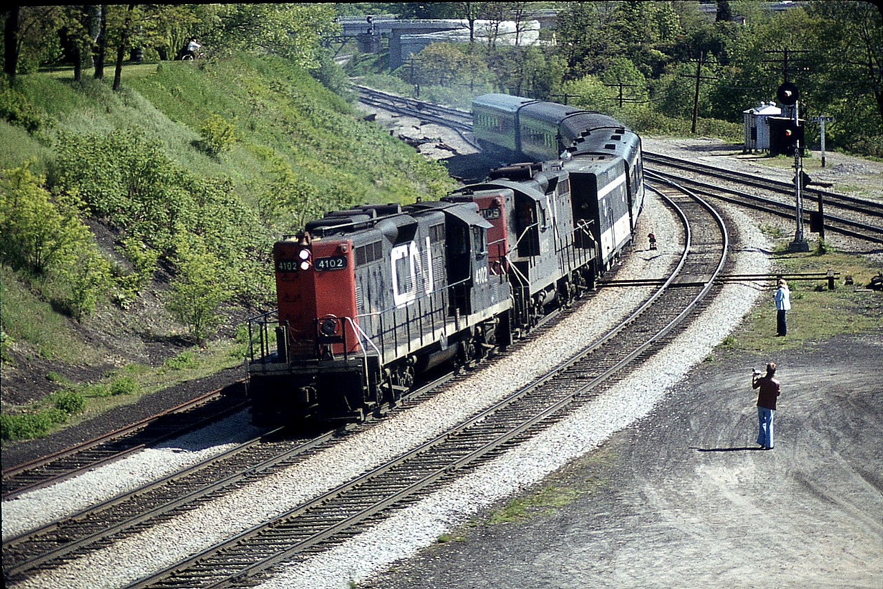 Two geeps and a jenny...........the head end almost equals the consist itself in this pre-VIA passenger image taken off the hillside at Bayview Jct. CN GP9s 4102 and 4105 along with steam jenny (number unknown)have but four cars in tow in this mid-morning westbound. I had talked a buddy as well as my old Sidekick into spending a couple of hours watching what was happening as the train-watching bug had really bitten me hard in those years. Note the trees are just beginning to sprout on the hillside, and the 'Railfans Walkbridge' in the background is but one year old.
