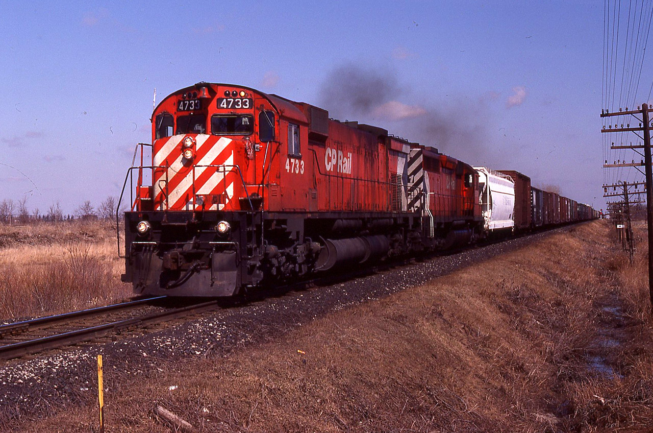 A westbound at Dillon Road with 4733 and an SD40-2 show the straight, flat terrain that exists on the Windsor Sub west of the Chatham diamond with CN. (the eastward Absolute signals can be seen in the distance). Much of the pole line is still in place, and an early spring comes to the 'Great Southwest'.