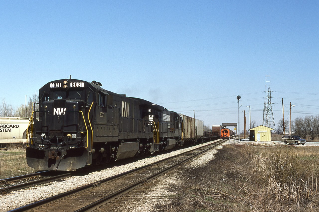 Westbound NS train 27, St. Thomas to Windsor, passes by the newly constructed CN Chatham East office and is about to cross the CSX diamond. A piece of track machinery is taking care of the eastbound roadbed, while covered hoppers fill the CN/CSX interchange. Train 27 has obviously stopped at one of the on-line elevators, as evidenced by the two hoppers behind the power. Barring further delay or work to be performed at the small CN yard, the train will be yarded at the water's edge in Windsor in about 90 minutes.