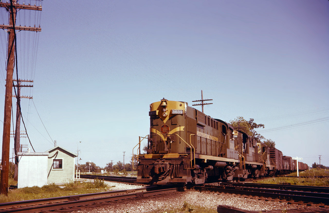 CN 3639 plus 2 others is operating as an Extra and may well be a Fort Erie-Sarnia train, such as 485. A crew member is taking in the nice weather as he leans out the cab window. Note the train order delivery hoop outside the NYC office, complete with a small ladder !