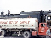 Fantrip attendees and railfans bearing cameras are stretching their legs during a stopover at Port Colborne on the July 10th 1960 UCRS fantrip. The crew of CNR Northern 6167 attend to her needs as she takes on water from one of A. Medvic of Wainfleet's tanker trucks.
