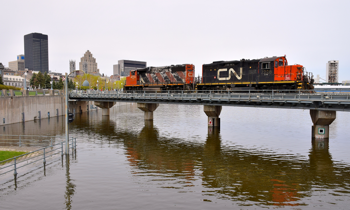 There is high water all over North America this spring, and where the Lachine Canal empties into the St. Lawrence River in Old Montreal is no exception. Here CN 4773 & CN are stopped on a bridge over the water, waiting for security to flag the crossings before they can proceed.