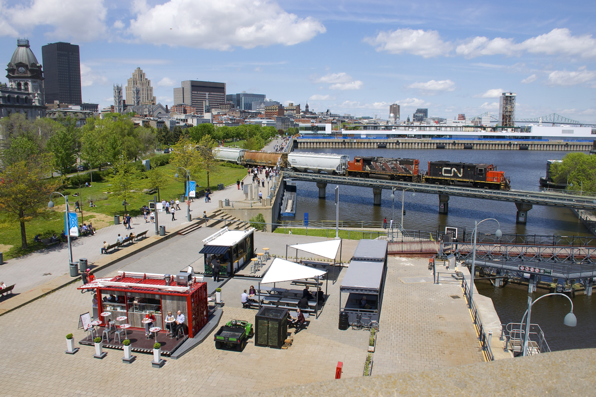 Closed as recently as last week (and since the end of last summer), I was glad to discover that the tower that I took this shot from (controlled by Parks Canada) was open at lunch today, especially since a friend had let me know that a CN transfer was leaving the port. Also open for the summer are food stands Tacobox and Muvbox, seen at bottom left. Seen from this elevated vantage point, CN 7228 & CN 4773 cross the Lachine Canal with 5 cars.