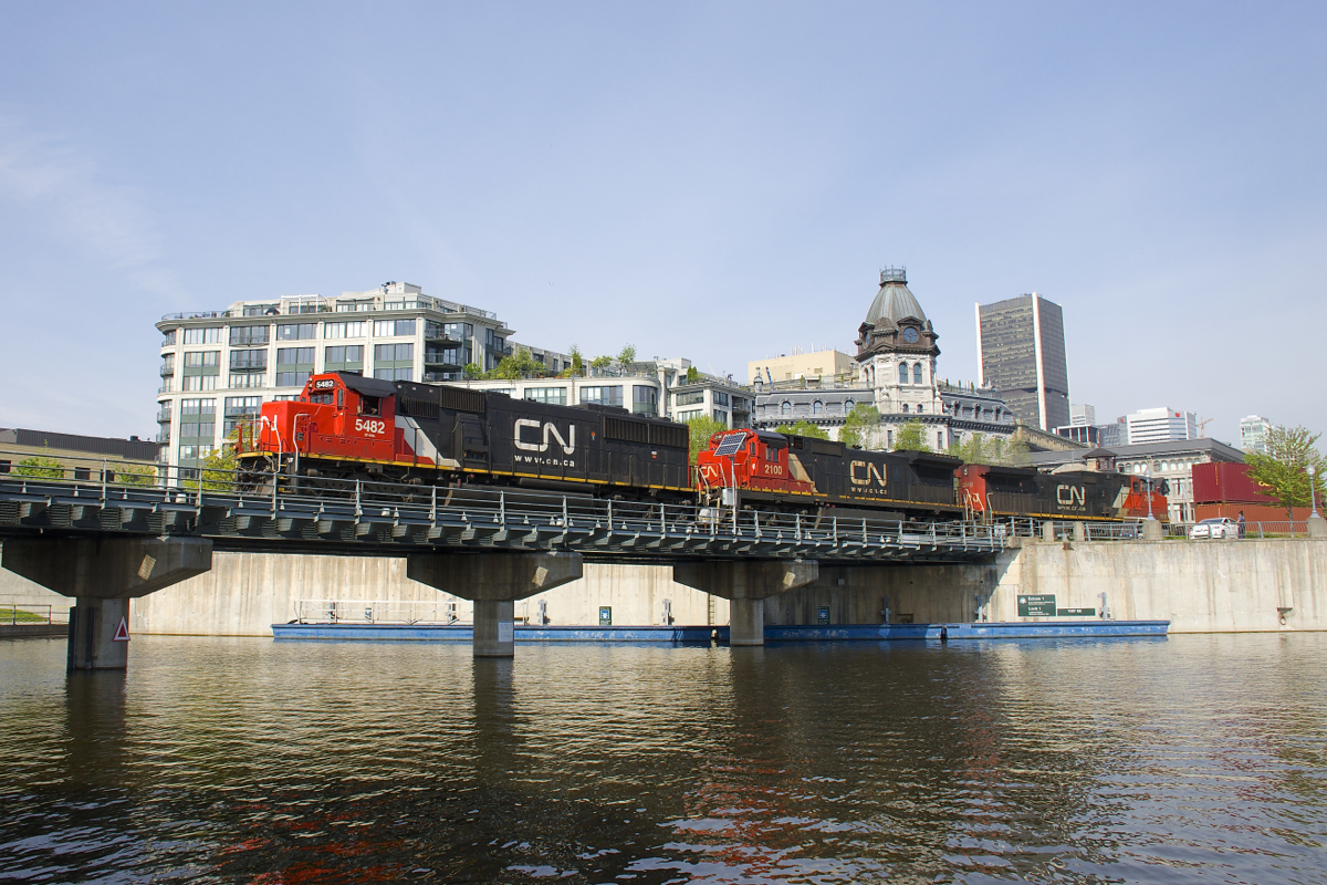CN 149 is leaving the Port of Montreal with two standard cab units that CN picked up secondhand (SD60 CN 5482 & C40-8 CN 2100), with CN 2648 third. The train is leaving the port a bit later than usual as it crosses the Lachine Canal.