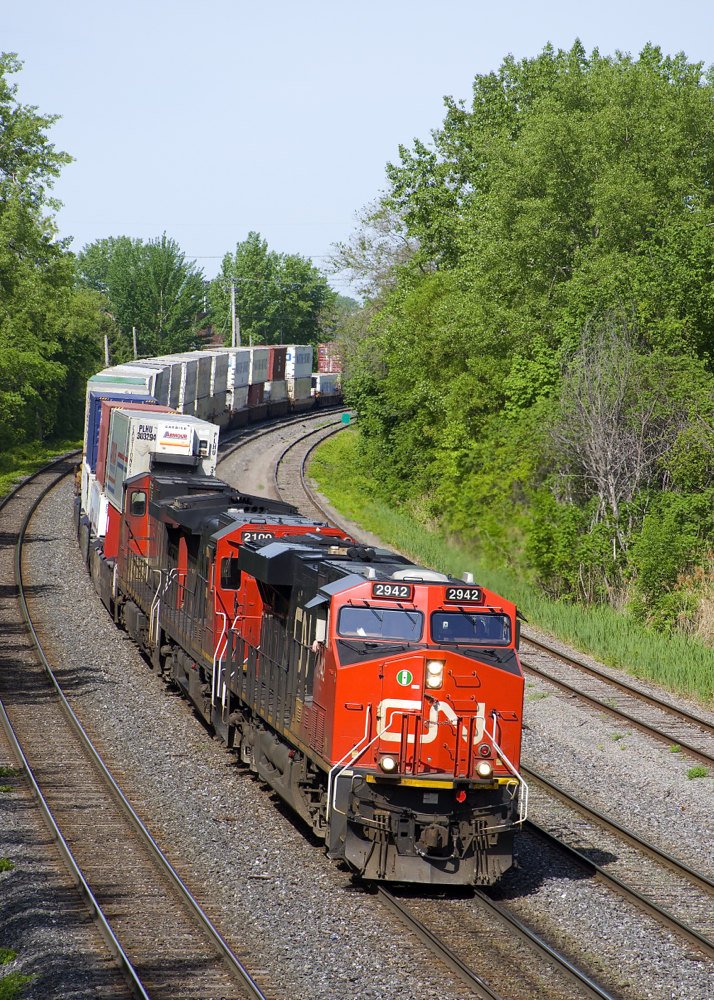CN 120 has CN 2942, CN 2100 & CN 2648 up front and CN 8853 as mid-train DPU as it rounds a curve on CN's Montreal Sub. This 640-axle long intermodal train originated in Toronto and will terminate in Halifax.