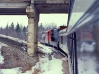 UNDER THE OVERPASS. Terra Transport Mixed Extra 935 West crosses under the TCH Overpass at Bishops Falls  shortly after leaving the station on April 16, 1988. This was the photographers's third trip on the mixed and the very first (and only) for his friend Paul. The two would be the only passengers for the entire 138 mile journey to Corner Brook with the exception of a lone cabin owner who boarded at Millertown Junction and departed at Gaff Topsail. A special treat for both riders was that the train left Bishops Falls with passenger only equipment (Baggage 1308 and Coach 764) and would remain a mini 'Caribou' until four container units were picked up in Grand Falls, thus making it a true mixed. With the completion of the Trans-Canada Highway in 1965, dozens of overpasses were constructed across the right of way throughout the Island but most, such as this one, have since been replaced with corrugated steel pipe to allow access for the Trans Canada Trail.   