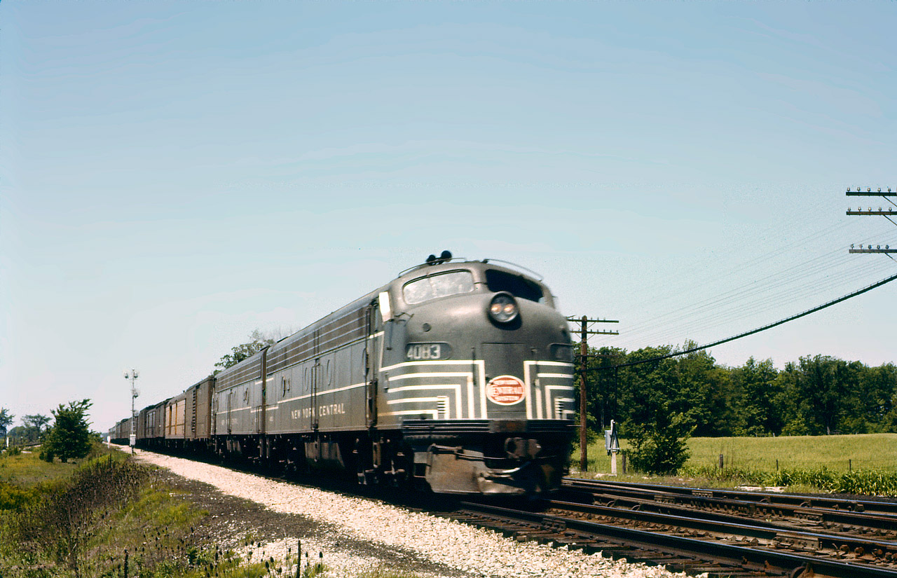 NYC 4083 and another E8 on what must be train 50, with at least 15 cars. The " head end " equipment is carrying the most revenue, a likely mixture of mail, express and baggage. The first car looks to be
an REA box (Railway Express Agency) while the 2nd car appears to be either UP or Milwaukee Road. The mainline crossovers are still in place at this time.