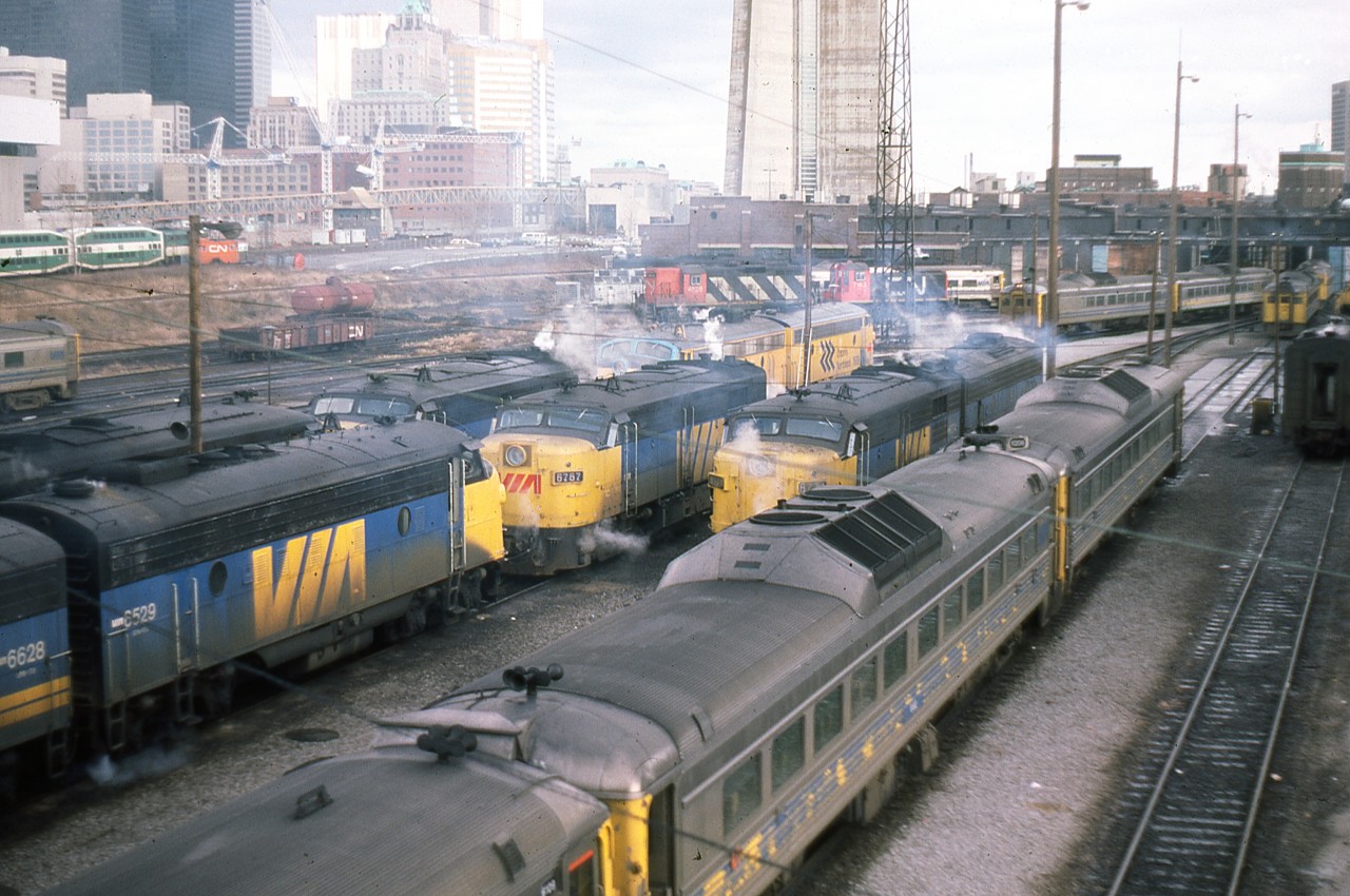 A Doug Lawson photo.
A candidate for the Time Machine.
Del Rosamond's 1961 photo - http://www.railpictures.ca/?attachment_id=17034
In May 1961, Del Rosamond stood on the Spadina Ave bridge and captured a bevy of GMD1's, sprinkled with cab units, switchers and geeps. Very few were carrying the new paint scheme introduced in 1960.
In December 1982, Doug Lawson stood in nearly the same position and captured a different look, although the end goal is the same - passenger service. Here we can see a matched pair of Ontario Northland FP7's, along with VIA F9's and FPA4's, plus a handful of RDC's. There are other things of course - the CN Tower is now in place, along with the elevated walkway for access. John Street interlocking is fully visible in both images, as opposed to today when you'd need to get on your knees to find it beneath the commercial growth. So which do you prefer ??