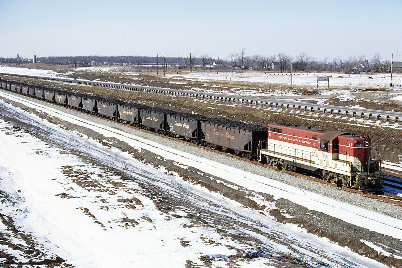 Looking for all the world like a P.R. pose, the original London product has a good jag of Lasalle coke as the Port Colborne local exits the east end of the (then) new Welland tunnel. Algoma Steel's Canada Furnace Company will be the recipient of this product. In turn they will manufacture Merchant Pig Iron, some of which TH&B will carry in a reverse move, for consumer's like Brantford's Massey Ferguson foundry (Verity Works). All is well in the world this January day, as myself and Fred Gaines stand freezing our eyeballs on the highway 140 overpass. And yes, 71 sounded very nice charging up the grade !