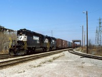 On Apr 30/85, Conrail operated the CASO for the final time. The next day CN and CP took title of the 225 or so miles of double track and sidings, yards etc.  Fast forward 2 years and CN has negotiated with Chessie ( almost  CSX) to have certain trains operate between their Chatham Sub and Fargo using trackage rights and 2 new connections. Since we’re still in the train order era, a new office was put into use named CN Chatham East. This was immediately south of the CN Chatham Sub and east of the C&O diamond, using an old connecting spur that once served Darling & Co ( renderings). On Apr 8/87, I caught NS train 327 as he passes through the truss bridge and beyond the Chatham East connecting track with SD40-2’s 3261-3313 (both delivered as Southern Rly when new) operating long hood forward. The new structure for the Chatham East operator is immediately behind me. The burnt remains of the former CIL fertilizer plant can easily be seen behind the bare trees/shrubs.