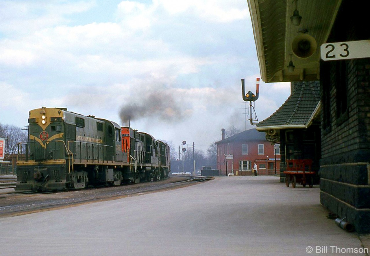 Canadian National RS18's 3864 and 3090 lead a sister unit on a westbound freight past Brantford Station, at Mile 23 of CN's Dundas Sub in May of 1965.