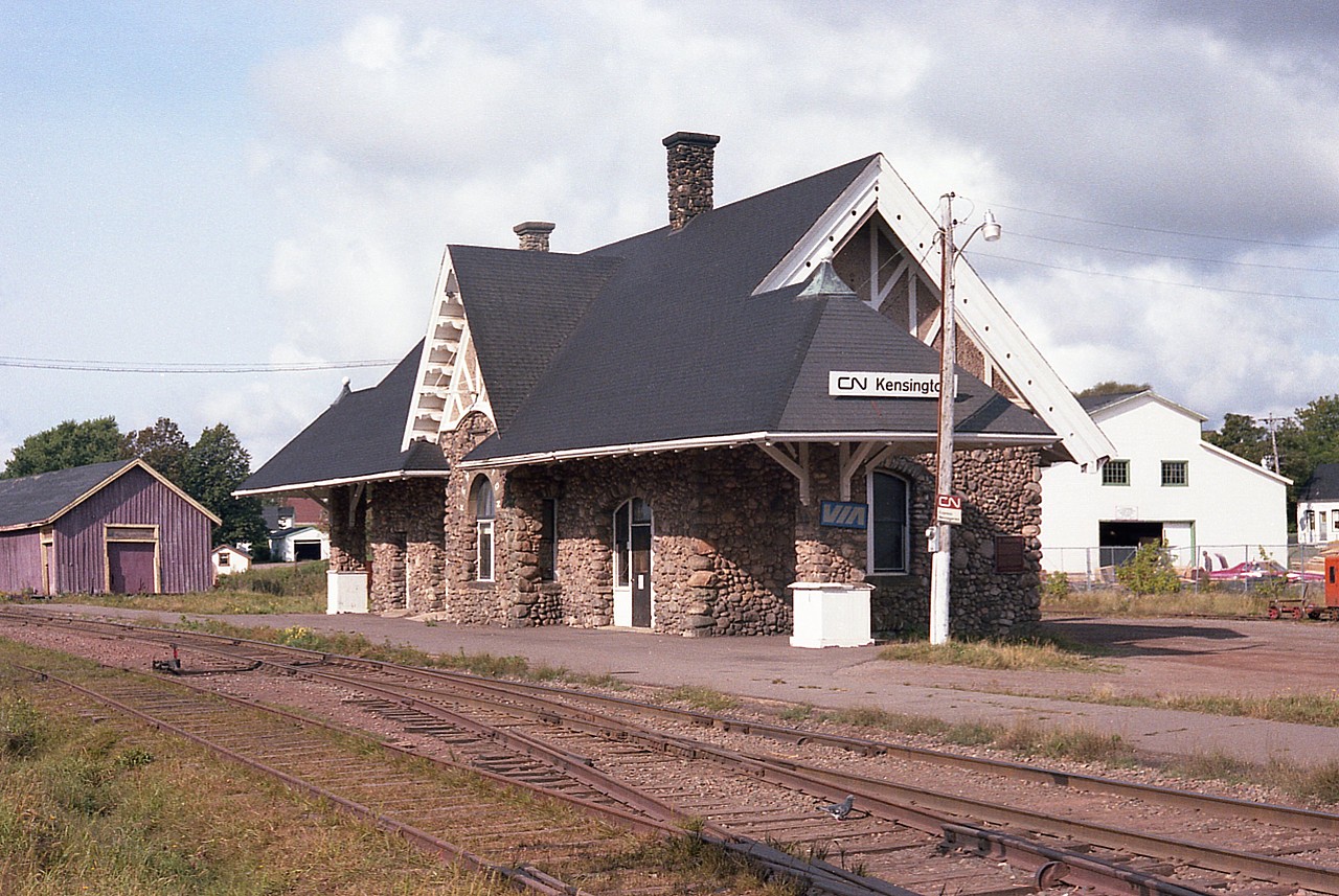 This is a charming place. Kensington still has two stations, survivors of the loss of the actual railroad way back in 1989. Kensington's first station burned down. A second one was built; it outlived its' usefulness and was moved to be a private residence just in behind where this third station stands. This fieldstone station (1905) was built just to the east of station #2, which was replaced by a freight shed in 1906, as seen in this 1981 photo. The old shed is now gone and a Liquor/beer store stands in its place, but the stone station is a Heritage Building, so hopefully it will live on for many years. When looking over this scene I questioned the "VIA" sign out front. Upon checking an old timetable I found this was for bus service.