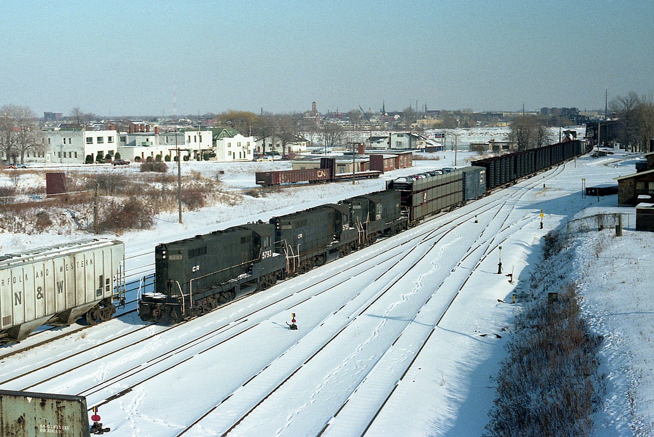 Here is an interesting view.  From up on the old Central Av overpass we see CR 5793, 5739 and 5795 bringing a transfer from Buffalo into Canada. Note all the truck frames. Note the fact this is 4 years after the formation of Conrail and all three GPs are still in either NYC or PC black. And the old connector is still in place in front of the passenger station........I used to refer to this as the 'NYC' line because when I first got to exploring down there, on the west side of the overpass was a "NYC Yard" sign, one of those old wooden namesigns we used to see so many of; and it was firmly fixed in the brush. So it couldn't go home with me. The 'B-1' Bridgeburg station is still in place at the International Bridge, as well the old CN Crew Hostel can be seen on the extreme right. And the track off to the right where Boeing cars were left for the aviation industry is still in. The CN station that was there is 6 years removed, otherwise I could have had three stations in one frame. Bridgeburg, which merged with Fort Erie still looks rather clean. Now, that street off on the left side is run down and decrepit. All these years this particular roll used in late 1980 was the only time I selected 'Blacks' film, strangely enough. Nothing against it; it turned out not too bad.