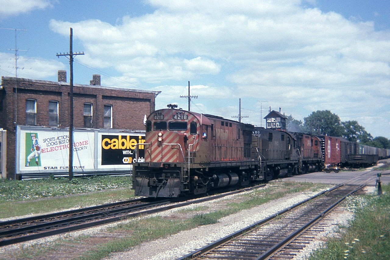 Crossing William St westbound in downtown Chatham is CP 4218 leading PNC 900 and an unknown unit. The crossing tower is visible in the background, the station is not.  Interesting old billboard on the left; we do not hear much of Electrohome any more.  And it looks like an "Expos" player depicted; the Blue Bores had not yet come into being. Regarding that second unit, I am quite sure it is number 900, as I had seen it before in Hamilton, but am unable to find any record of it.  No doubt one of our RP experts will be able to help me out.