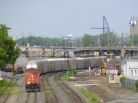 <b>A new (but short-lived) angle.</b> CN 401 rounds a curve at Turcot West with CN 5759 & CN 2826 for power and loaded autoracks on the head end as always. This angle opened up just recently, as up until a few months ago trees along the south side of the ROW blocked this shot. However this shot will change in the near future, as CN's ROW here will head to the left soon, with a switch to the new ROW already visible at far left; this will also mean the replacement of the classic signal bridge that the train is passing under. One more change is that trains that change crews at Turcot West are now doing so where the tiny shack is at right; before trains changed crews a few hundred metres further east.