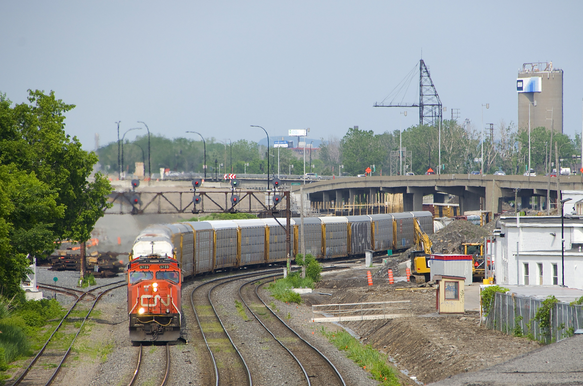 A new (but short-lived) angle. CN 401 rounds a curve at Turcot West with CN 5759 & CN 2826 for power and loaded autoracks on the head end as always. This angle opened up just recently, as up until a few months ago trees along the south side of the ROW blocked this shot. However this shot will change in the near future, as CN's ROW here will head to the left soon, with a switch to the new ROW already visible at far left; this will also mean the replacement of the classic signal bridge that the train is passing under. One more change is that trains that change crews at Turcot West are now doing so where the tiny shack is at right; before trains changed crews a few hundred metres further east.