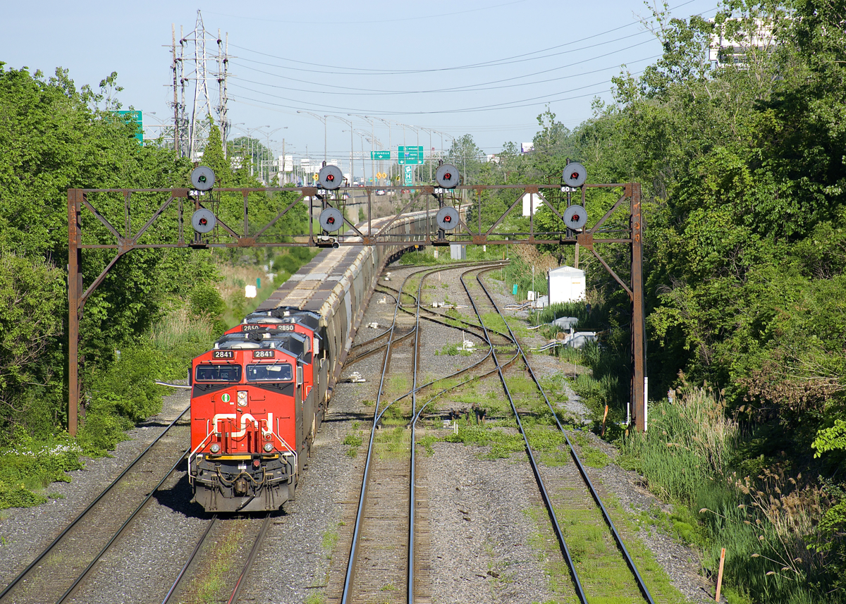 It's a busy morning on CN's Montreal Sub as CN B730 passes under the signal gantry at Ballantyne, just east of the eastern entrance to Taschereau Yard. CN 149 is lined on the south track at far left, CN 305 is just behind it and CN 529 has just entered Taschereau Yard. Loaded potash train has the usual complement of 4 AC units (CN 2841 & CN 2850 up front and DPU's CN 2958 & CN 2966) and 205 cars.