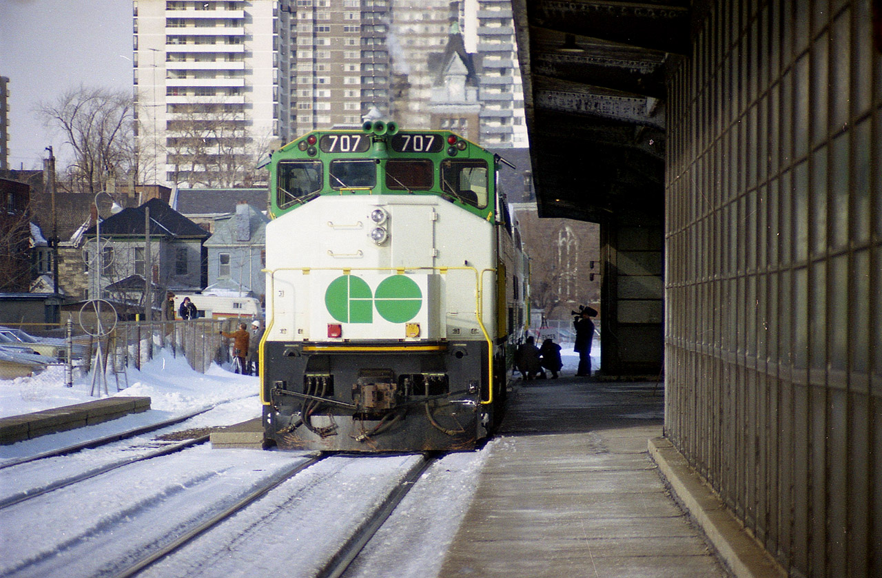 GO Bi-levels come to Hamilton! A special two car GO train came to Hamilton on the 1st of February 1978 to show off the new bi-level cars to the potential commuters. There was an APCU unit on the other end of this short train; I elected to submit this head on view rather than a 3/4 shot as we can see media activity taking place here. Two media people are crouched down as CHCH Ch 11 cameraman records an interview on the right side, and to the left train personnel (videographers)are chatting it up with a couple of fans setting up their own video cameras on the other side of the fence.
This was the start of how we know it today. The first GO Bi-levels were built in 1977-1978. The GO 707 pictured became CN 9674 in 1991.