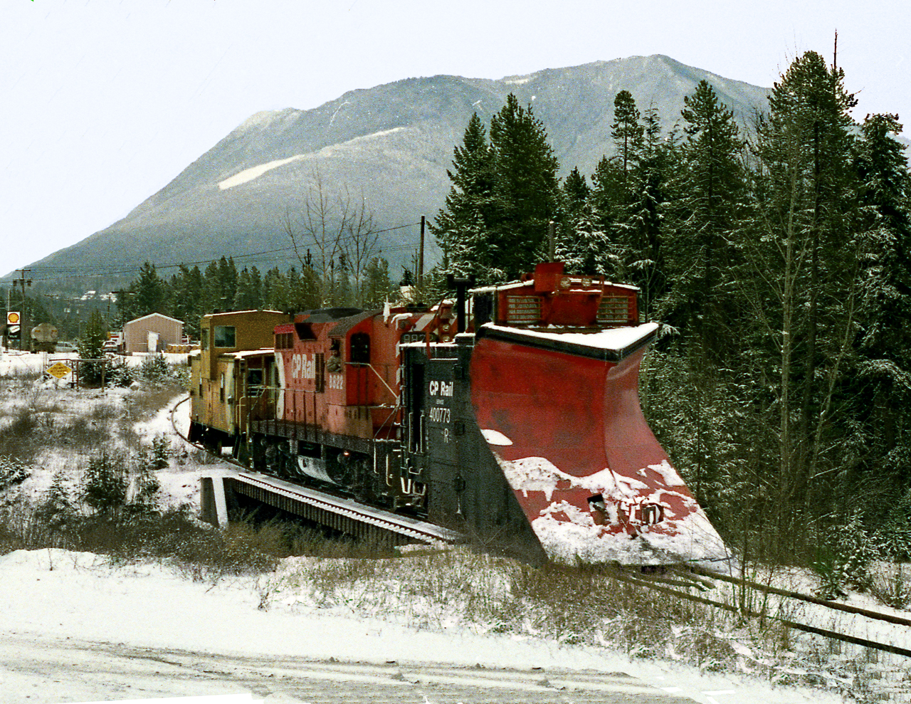 Prior to the last run on the isolated Kaslo Subdivision, only accessed by car barge on Slocan Lake, the crew rounds up M of W equipment stored at Nakusp. The train crosses Kuskanook River headed to the wye where snow plow will be put in trailing position for trip to Rosebery
