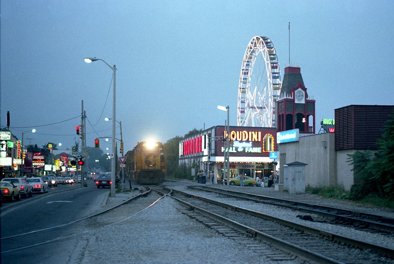 A few years ago I posted an image of C&O 4291 and 4173 rumbling thru Clifton Hill tourist area of the falls, but recently found this image which I consider a lot better. It was taken hand held, as I had to jump out of the car and 'grab' the shot; the train is just entering Clifton Hill and it is interesting to see all the tourists milling around and the traffic backed up. Some of the business signs are readable and the fact the Houdini tourist joint is so prominent in my opinion makes the picture. A lot has changed since this shot from 1980. Of course the railroad has left town and all that, but the Houdini "store" has left as well. Currently the location is occupied by "Ripley's Moving Theater". The industrial track enabled the local CP to service the cereal company a block or so over, Shreddies were made there.............. all gone.  Seeing how the tourist business has grown leaps and bounds and the area is packed with visitors from all around the world, one could only image what they would think if big noisy smelly grubby freight trains still interrupted their evenings. :o)