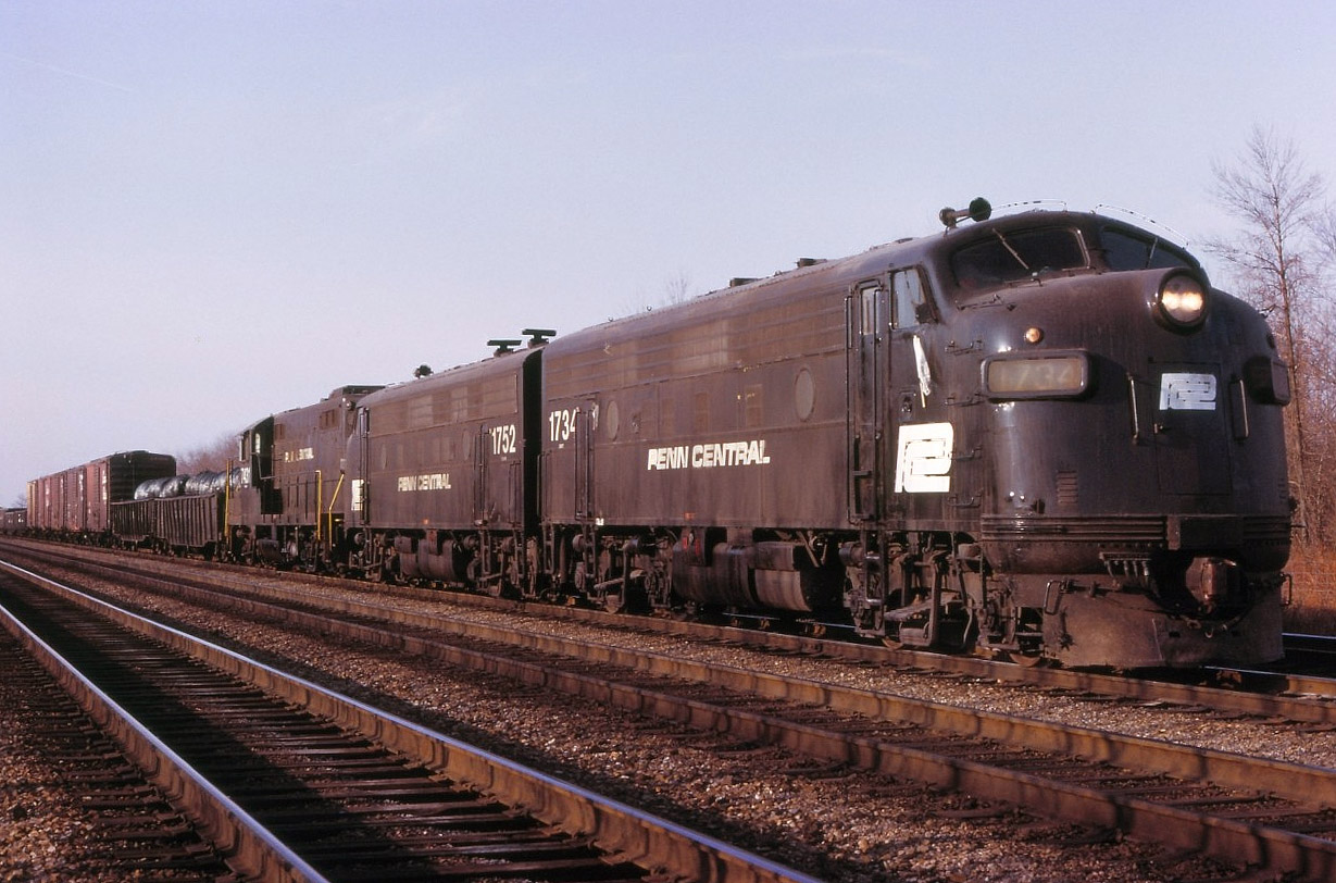 Perhaps this may look like any random photo in the northeastern USA, but, in fact this is on the original North Service track at Aldershot ! Joint Buffalo-Toronto train Penn Central FT-1, nicknamed KINNEAR by TH&B and CPR, is headed east for Toronto on a somewhat mild Wednesday in January. But it's taking him over an hour to move from Hamilton Junction to Burlington East, owing to a malfunction on the main track(s) in between Waterdown Road and King Road. Approaching Waterdown Road, the train was on the South main, then got crossed over and into the North Service, and then back out again onto the North main. My notes do not tell me what the malfunction could have been ( broken rails, damaged equipment, ...whatever). I took this photo just west of the King Road crossing and beside the half-cantilever signal that used to be there, as the 84 car train was moving through the service track.
NOTE - the first and 3rd engine numbers are interchangeable with each other !