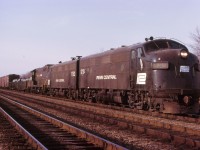 Perhaps this may look like any random photo in the northeastern USA, but, in fact this is on the original North Service track at Aldershot ! Joint Buffalo-Toronto train Penn Central FT-1, nicknamed KINNEAR by TH&B and CPR, is headed east for Toronto on a somewhat mild Wednesday in January. But it's taking him over an hour to move from Hamilton Junction to Burlington East, owing to a malfunction on the main track(s) in between Waterdown Road and King Road. Approaching Waterdown Road, the train was on the South main, then got crossed over and into the North Service, and then back out again onto the North main. My notes do not tell me what the malfunction could have been ( broken rails, damaged equipment, ...whatever). I took this photo just west of the King Road crossing and beside the half-cantilever signal that used to be there, as the 84 car train was moving through the service track.
NOTE - the first and 3rd engine numbers are interchangeable with each other !